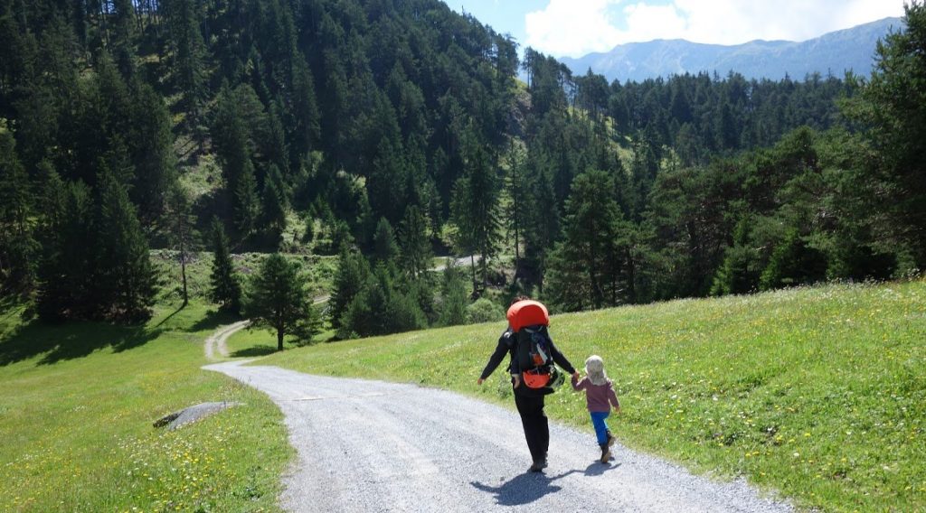 Mutter und Tochter rennen Hand in Hand einen sonnigen Feldweg hinab
