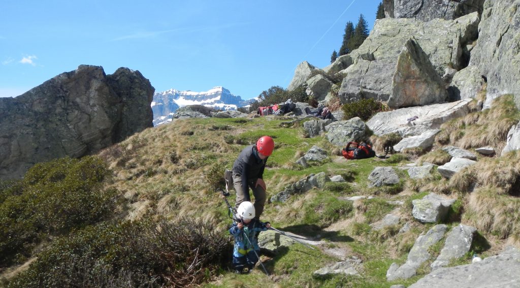 Kleines Kind und Mutter in den Bergen, mit Spielen mit Wanderstock beschäftigt