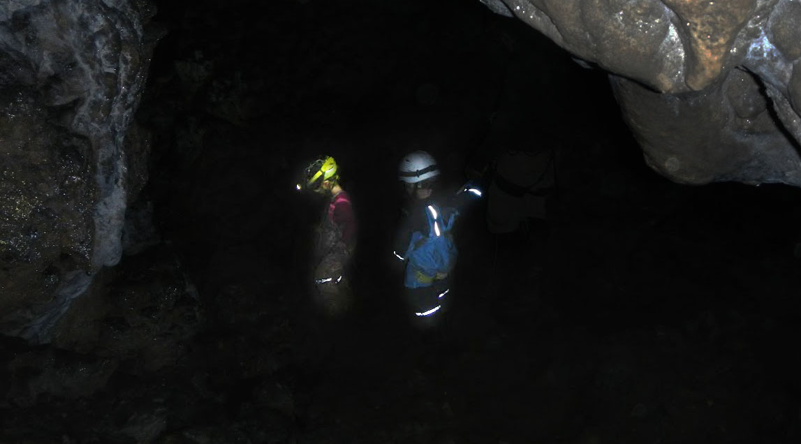 Kleine Kinder mit Stirnlampen in dunkler Höhle