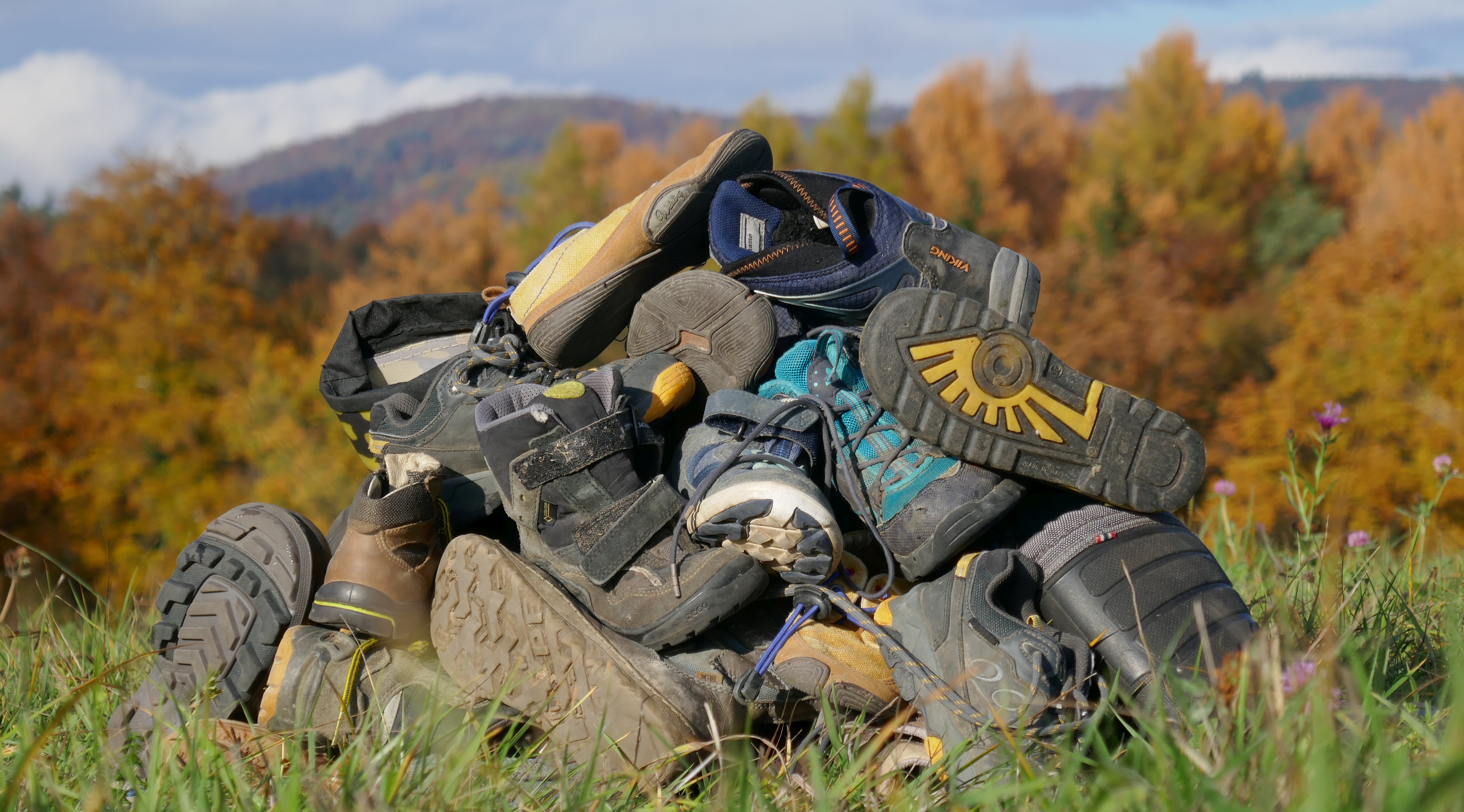 Ein Berg von Schuhen vor herbstlichen bewaldeten Hügeln