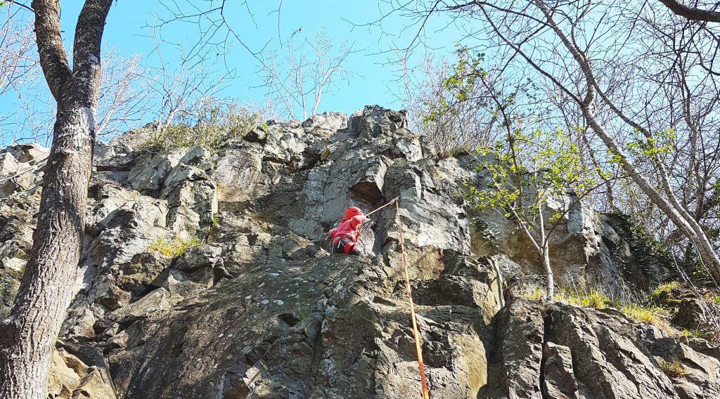 Felsklettern: Kind klettert am Seil in der Sonne