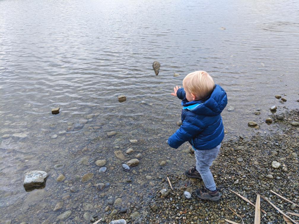 Kleines Kind wirft Stein ins Wasser