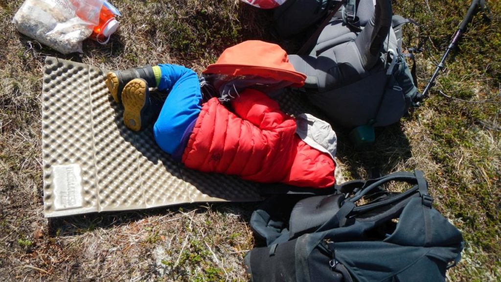 Kind schläft auf Isomatte im Heidekraut