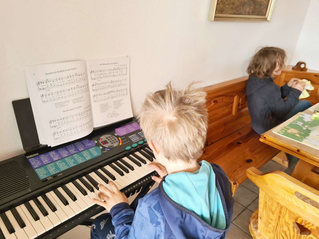 Kinder spielen Keyboard und basteln am Tisch