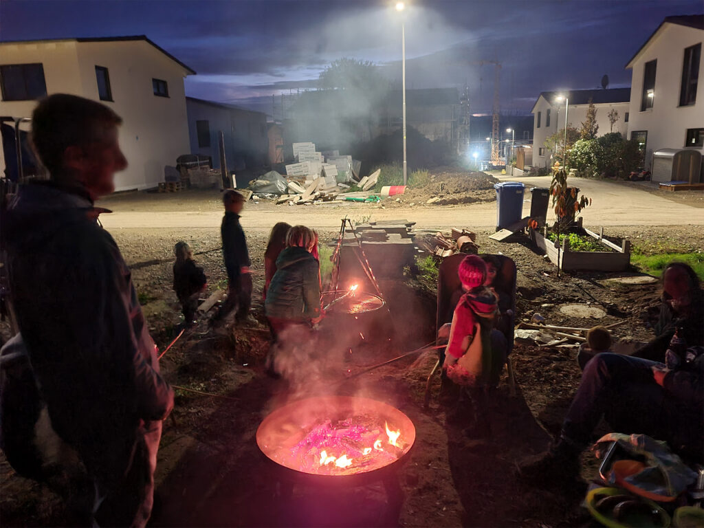 Feuer in der Feuerschale und glückliche Kinder vor dem Haus