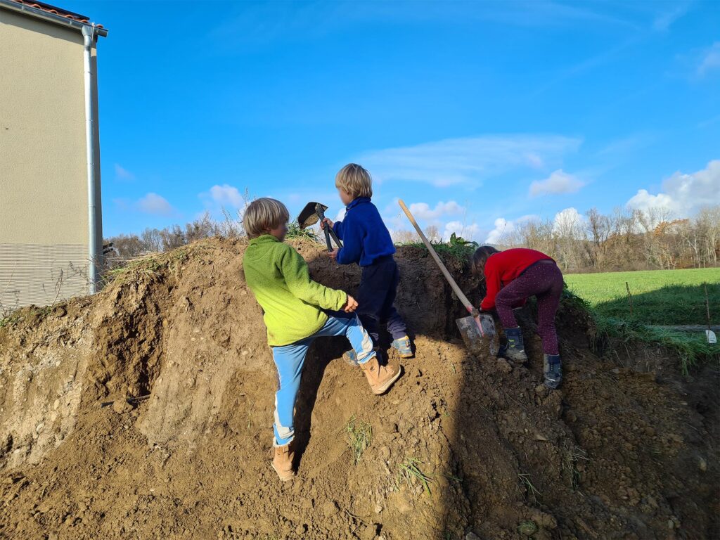 Der Hügel mit Mutterboden wird von den Kindern bearbeitet